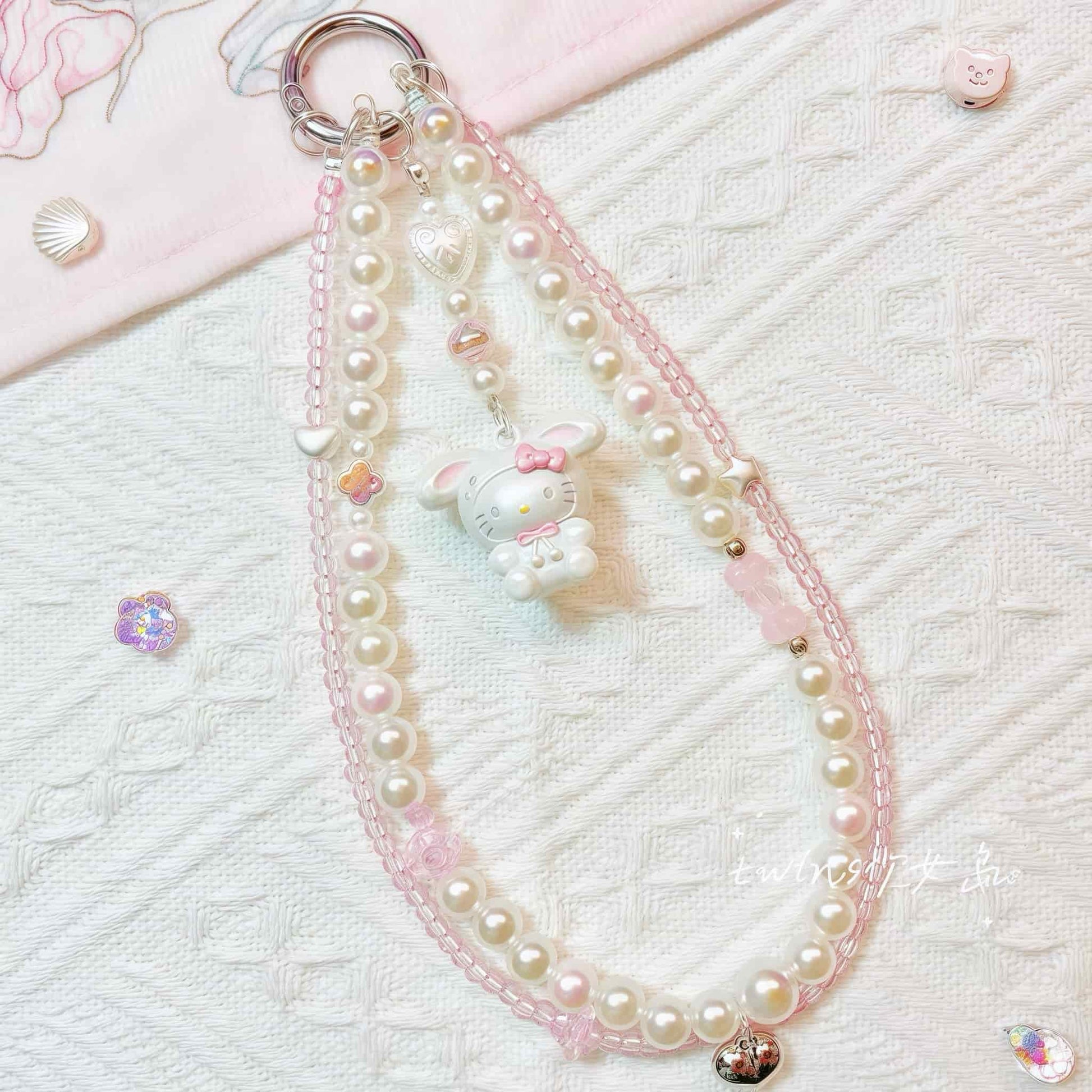 Close-up detail of Y2K style Hello Kitty decoden phone case with baroque pearls and pink accents